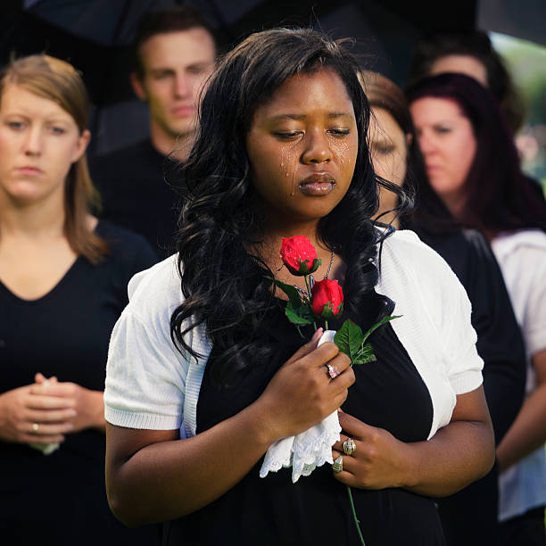 A grieving woman standing graveside at a funeral.